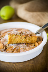 sweet apple pie in ceramic form on a wooden