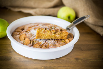 sweet apple pie in ceramic form on a wooden