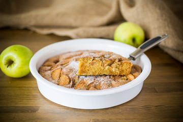 sweet apple pie in ceramic form on a wooden
