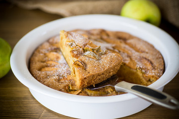 sweet apple pie in ceramic form on a wooden