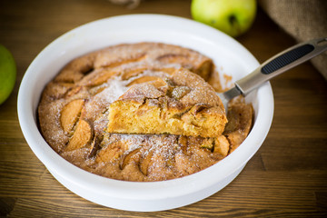 sweet apple pie in ceramic form on a wooden