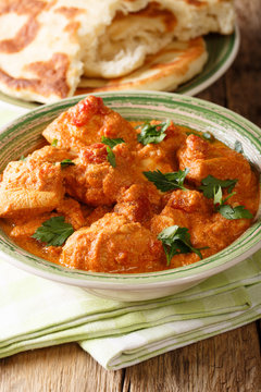 Indian Karhai chicken in a spicy sauce close-up served with naan bread. vertical