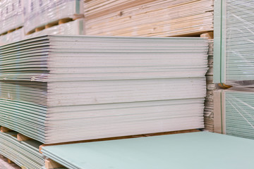 Gypsum plasterboard in the pack. The stack of gypsum board preparing for construction. Pallet with plasterboard in the building store. Construction Materials. Drywall warehouse.