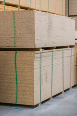 lumber osb, plywood, mdf, project panel at hardware store in USA. Wooden bars, flake board, sterlingboard on shelves inside lumber yard of home improvement retailer. Customer shopping. vertical photo