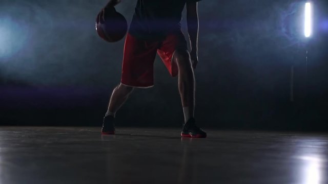 A solo basketball player does some dribbling moves in front of the camera