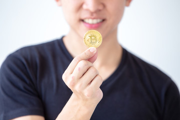 Young asian man hold golden bitcoin coins in hand. Virtual currency. Crypto currency. New virtual money.