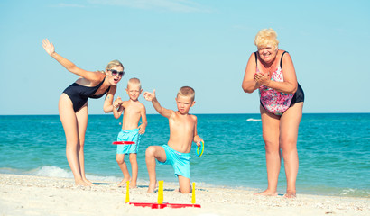 Children together with their mother and grandmother playing a game throwing rings on the beach	