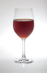 Glass goblet with wine stands on glass on  white background
