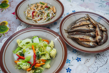Assorted Indonesian home made food served on plates : kentang balado, sayur cap cay, ikan goreng, tumis toge tahu