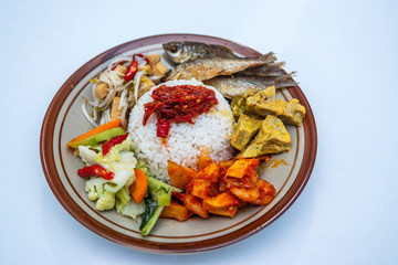 Indonesian style nasi campur with ikan goreng, gulai nangka, kentang balado, sayur capcay and tumis toge tahu