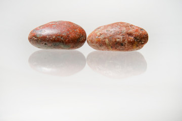 Beautiful pebble stones on a reflective white surface     