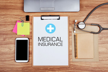 Clipboard with text MEDICAL INSURANCE and stethoscope on wooden desk, Healthcare and Medical Concept