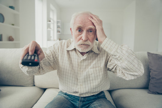 Portrait Of Nice Shocked Stylish Old Man Sitting On Divan Wearin