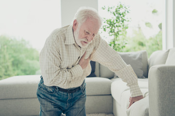 Sad tired stylish old man wearing checked shirt leaning on divan