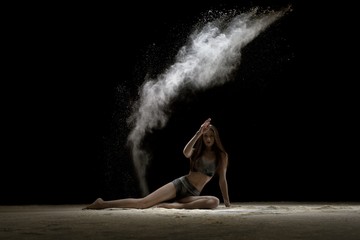Fototapeta na wymiar Girl in lingerie sitting in the dust in the dark