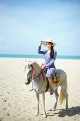 Beautiful woman riding a white horse at the beach