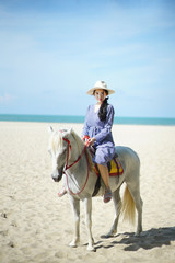 Beautiful woman riding a white horse at the beach