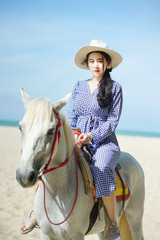 Beautiful woman riding a white horse at the beach