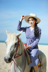 Beautiful woman riding a white horse at the beach