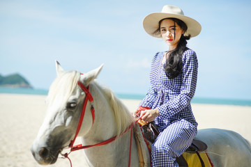 Beautiful woman riding a white horse at the beach
