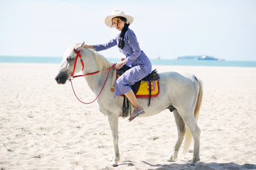 Beautiful woman riding a white horse at the beach