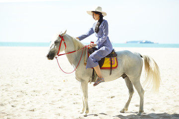 Beautiful woman riding a white horse at the beach