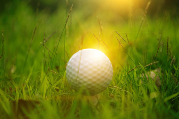 Blurred golf ball on tee in beautiful golf course at sunset background.