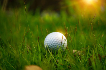 Blurred golf ball on tee in beautiful golf course at sunset background.