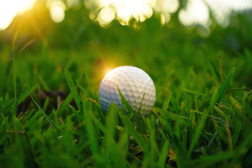 Blurred golf ball on tee in beautiful golf course at sunset background.