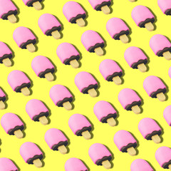 Creative art made with pink ice cream pattern on yellow background.