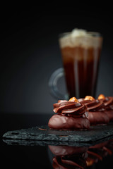 Chocolate dessert with hazelnut and coffee with cream on a black background.