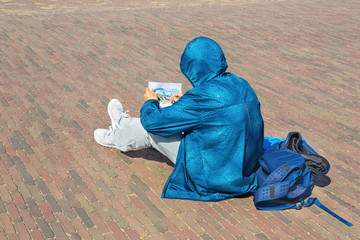 Young man in blue jacket draws out on the street