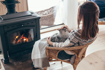 Human with cat relaxing by the fire place