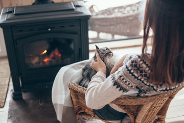 Human with cat relaxing by the fire place