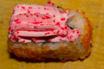 sushi roll with salmon, cucumber, cream cheese, caviar tobiko and masago on wooden background