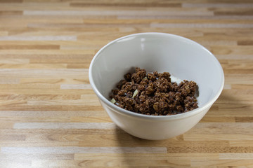 Chocolate corn flake with white and brown chocolate in white bowl on wooden desk