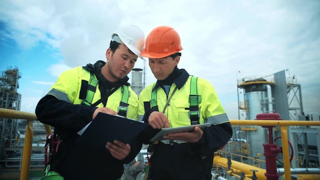 Two factory workman check and discussing working technology with paper document and tablet pc