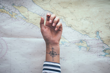 Compass tattoo on sailor ankle with nautical chart in background