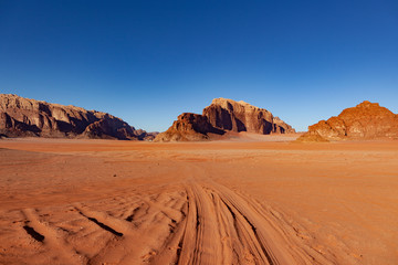 Fototapeta na wymiar Red Desert Landscape of Wadi Rum in Jordan, with a sunset, stones, mountains and the sky.