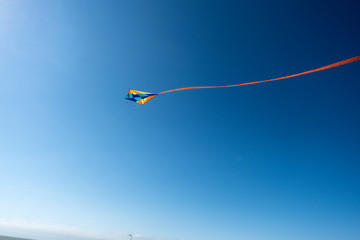 Colorful kite flying with with red ribbon
