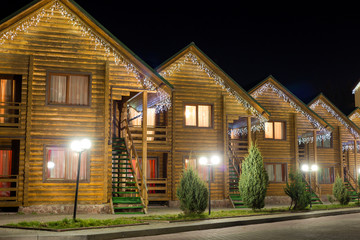 Row of new two-storied ecological wooden comfortable decorated cottages hotels on clean illuminated...