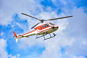 Hélicoptère de sauvetage en hélicoptère volant sur ciel / hélicoptère mouche rouge blanc sur ciel bleu avec nuages bon air jour lumineux