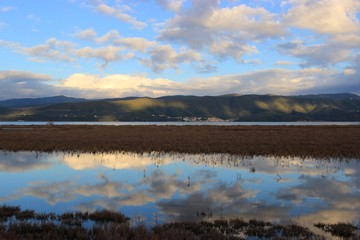 Background view of Menidi village in Aetolia-Acarnania at the shore of calm blue sea of Ambracian (Amvrakikos) gulf green hills mountains shadows of the clouds from the Koprena lighthouse in Greece