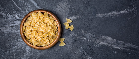 Italian raw farfalle pasta on black marble background