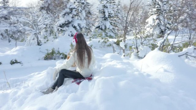 A young girl walks in the winter forest with a basket of mandarin.