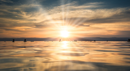 Dead Sea - October 05, 2018: Tourists bathing in the salty Dead Sea by sunset, Jordan