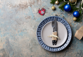 Obraz na płótnie Canvas Christmas table setting on decor background. Blue and gray plate, cutlery, festive decorations.