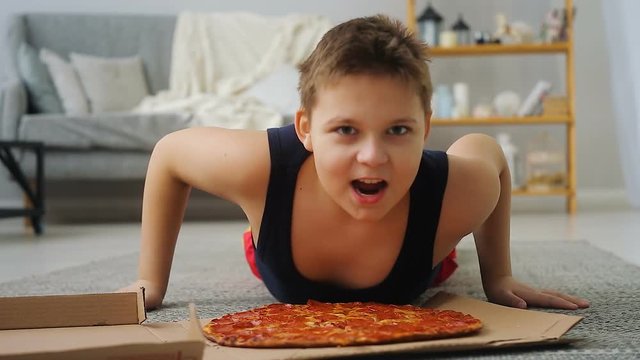 boy doing push-UPS from the floor where the pizza is