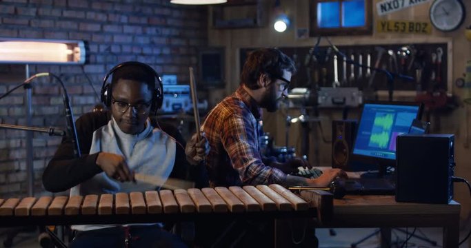 Medium long shot of young men recording music in home studio