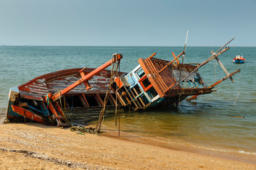 fishing boat crashed lies on its side near the shore, old shipwreck or abandoned shipwreck